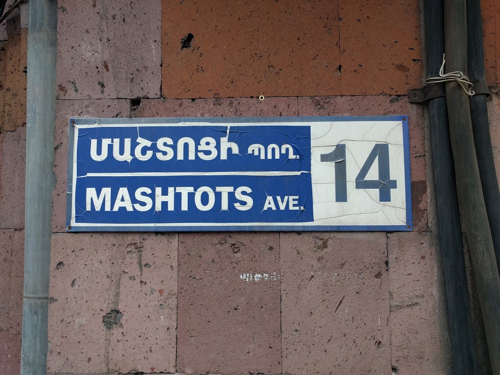 A plaque set in both Armenian and Cyrillic scripts on the side of a building in Yerevan honoring Mesrop Mashtots, the inventor of the Armenian alphabet.