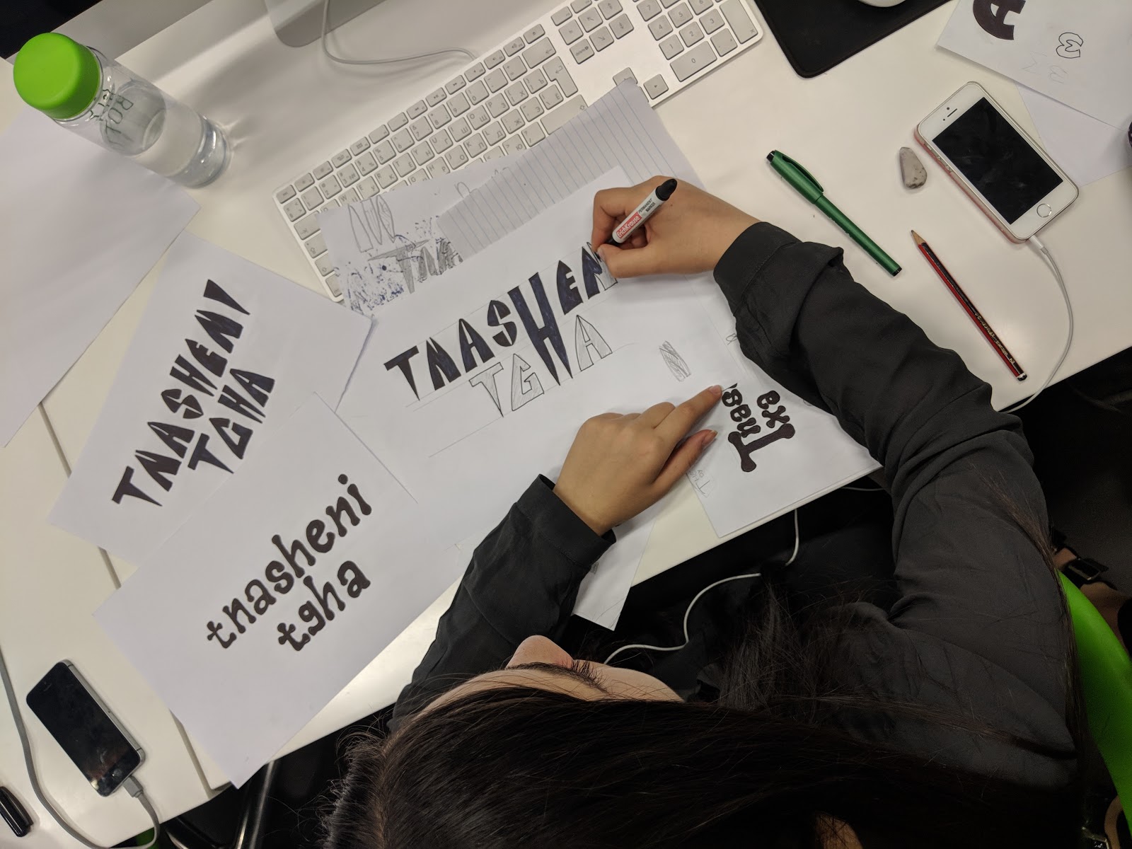 Overhead shot showing a female student working on some lettering with a magic marker.